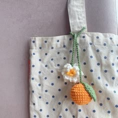 an orange and white crocheted bag hanging from a hook on a wall with polka dots