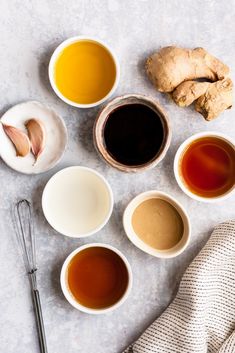 several different types of teas and spoons on a white surface with a cloth