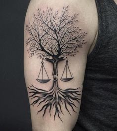 a man with a tree and balance scale tattoo on his arm