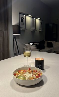 a bowl of food and a glass of wine on a table