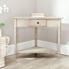 a white table with two drawers and a book on it next to a potted plant