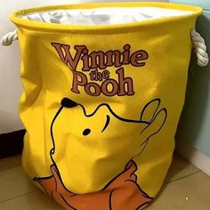 a yellow winnie the pooh bag sitting on top of a floor next to a wall