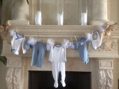 baby clothes hanging from a mantle in front of a fire place with candles on it