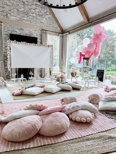 a living room filled with lots of pillows and pink decorations on top of the floor