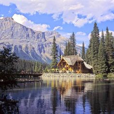 a lake surrounded by trees and mountains under a blue sky