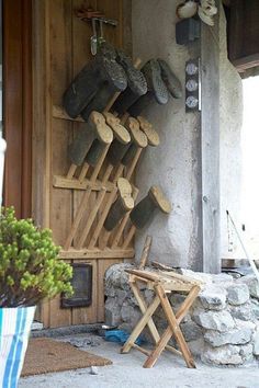 a bunch of shoes that are hanging up on the side of a building and some chairs