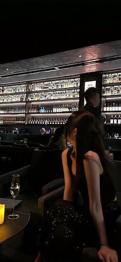 a woman sitting at a table with a glass of wine in front of the bar