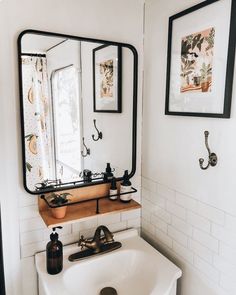 a bathroom sink sitting under a mirror next to a wall mounted faucet with soap dispensers on it