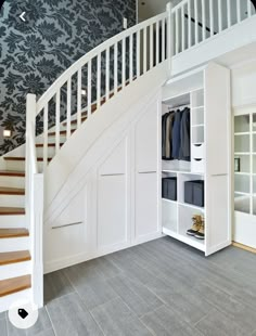 an open closet under the stairs in a house with blue wallpaper and wooden flooring