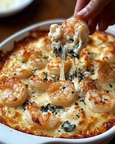 a person scooping some food out of a casserole dish with shrimp and spinach