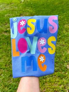 someone is holding up a blue bag with the words jesus loves me written on it