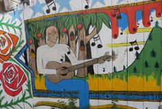 a mural on the side of a building with a man playing guitar in front of it