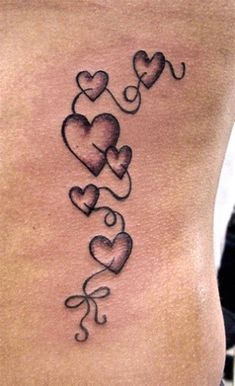 a woman's stomach with three hearts and the word love tattooed on her side