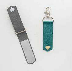 a key chain with a heart on it sitting next to a card holder that has a metal clip attached