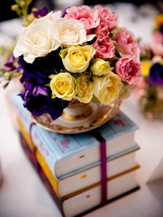 a bunch of flowers that are on top of some kind of books in a vase