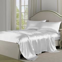 a bed with white sheets and pillows in a room