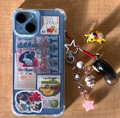 an iphone case with various items on it sitting next to a key chain and charm