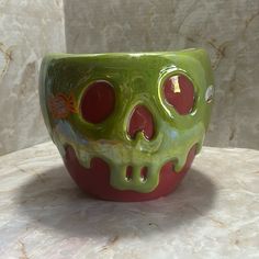 a green and red bowl sitting on top of a marble counter next to a white wall