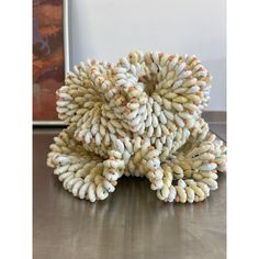 a sculpture made out of white and orange beads on top of a wooden table next to a painting