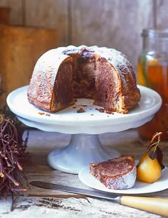 a bundt cake sitting on top of a white plate next to some sliced fruit