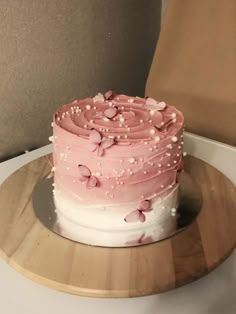 a pink and white cake sitting on top of a wooden plate