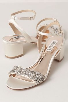 a pair of white high heeled shoes with crystal embellishments