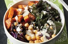 a bowl filled with vegetables and dressing on top of a green table cloth next to a fork