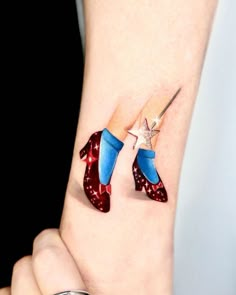 a woman's wrist with two red, white and blue shoes on top of each other