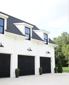 a large white house with three black garage doors