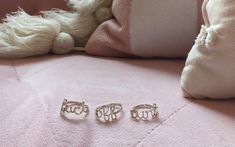 two silver rings sitting on top of a pink blanket next to a white teddy bear