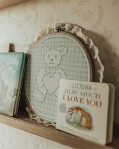 some books are sitting on a shelf next to a cross stitch teddy bear and a book