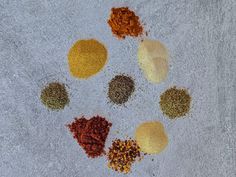 five different types of spices arranged in a circle on a gray surface with white background