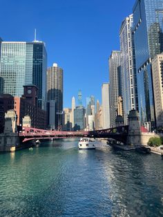 a boat is going down the river in front of some tall buildings and a bridge