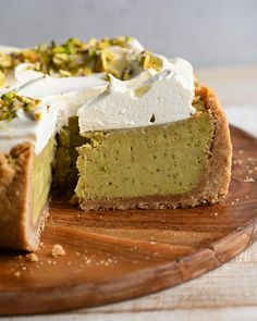 a piece of cake with white frosting and pistachio topping on a cutting board