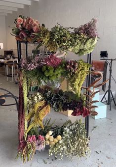 an arrangement of flowers is arranged on a shelf in the middle of a room with tables and chairs