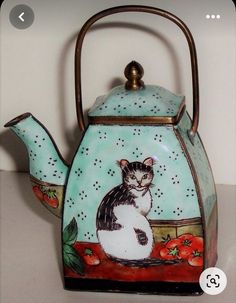 a tea kettle with a cat painted on it