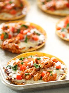 small pizzas with chicken and tomatoes on them