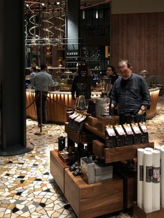 a man standing in front of a counter filled with wine bottles