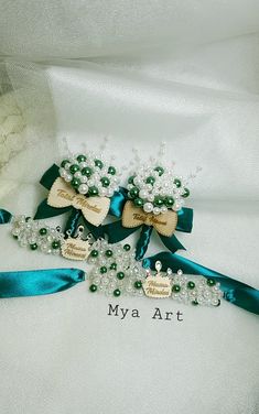 two brooches with bows and pearls on them are sitting on a white cloth