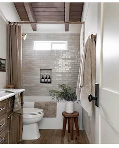 a white toilet sitting next to a bath tub in a bathroom under a wooden ceiling