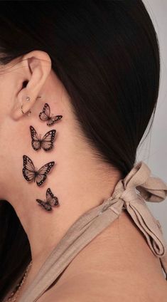 a woman's neck is adorned with three butterflies on the back of her neck