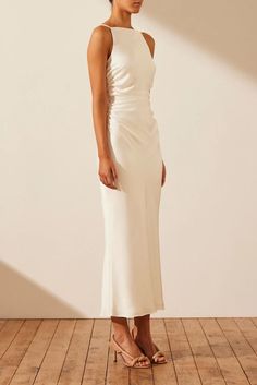 a woman in a white dress stands on a wooden floor and looks off to the side