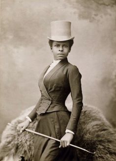 an old black and white photo of a woman wearing a hat with a cane in her hand