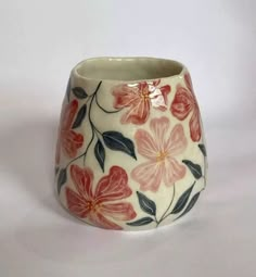 a white vase with red flowers painted on it