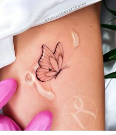 a woman's stomach with a butterfly tattoo on the side, and pink gloves next to it