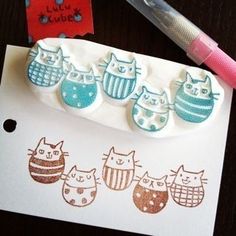 a rubber stamp with cats on it next to a piece of paper and a pen