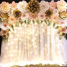 an arrangement of paper flowers and lights decorates the backdrop for a wedding or special event