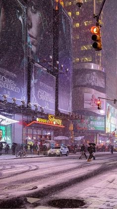 a city street filled with lots of traffic and tall buildings covered in snow at night