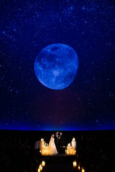 a large screen with candles lit up in front of it and a full moon overhead