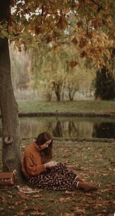 a woman sitting on the ground next to a tree